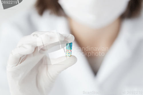 Image of close up of scientist holding pill in lab