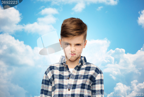 Image of angry boy in checkered shirt over blue sky