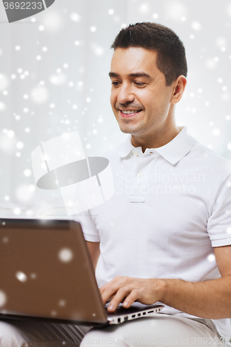 Image of happy man working with laptop computer at home