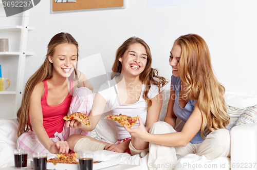 Image of happy friends or teen girls eating pizza at home