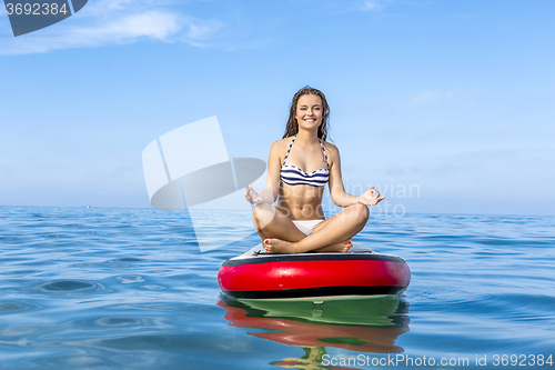 Image of Woman relaxing over a paddle surfboard