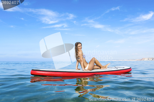 Image of Woman sitting over a paddle surfboard