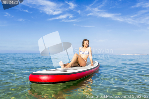 Image of Woman sitting over a paddle surfboard