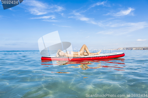 Image of Woman relaxing over a paddle surfboard