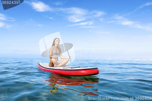 Image of Woman relaxing over a paddle surfboard