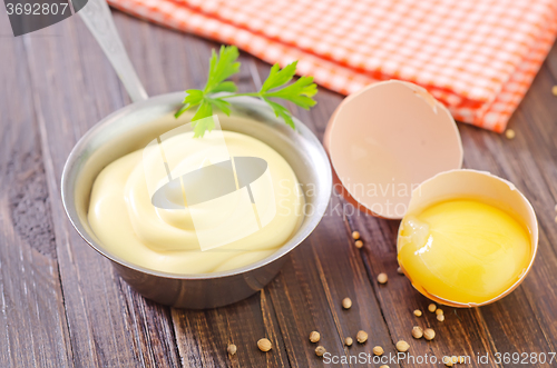 Image of mayonnaise in metal spoon on wooden board