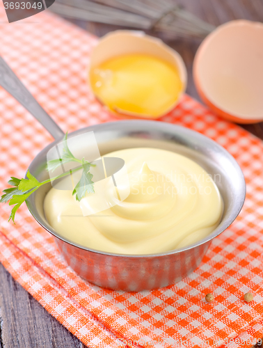 Image of mayonnaise in metal spoon on wooden board