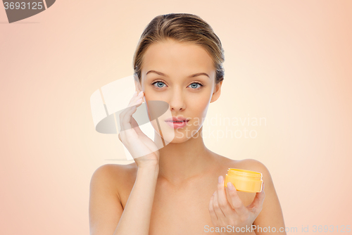 Image of young woman applying cream to her face
