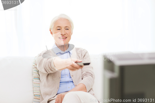 Image of happy senior woman watching tv at home