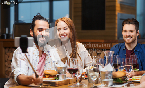 Image of friends taking selfie by smartphone at restaurant