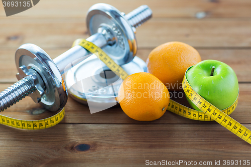Image of close up of dumbbell, fruits and measuring tape