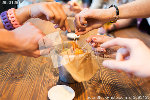 Image of close up of people hands taking cheese balls