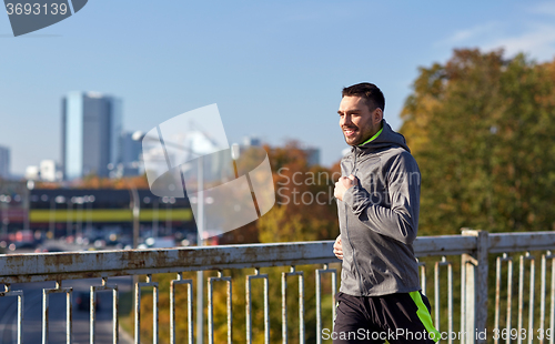 Image of happy young man running over city bridge
