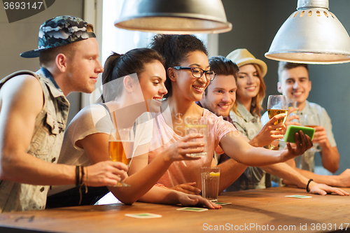 Image of happy friends with smartphone taking selfie at bar