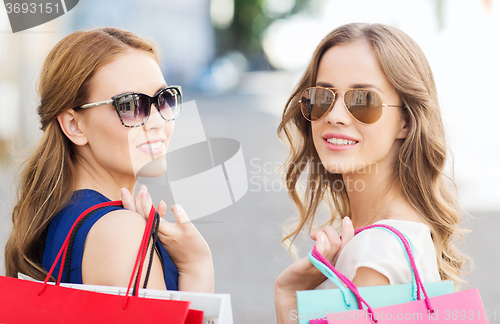 Image of happy young women with shopping bags in city