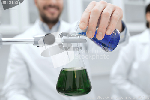Image of close up of scientist filling test tubes in lab