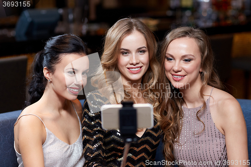 Image of women with smartphone selfie stick at night club