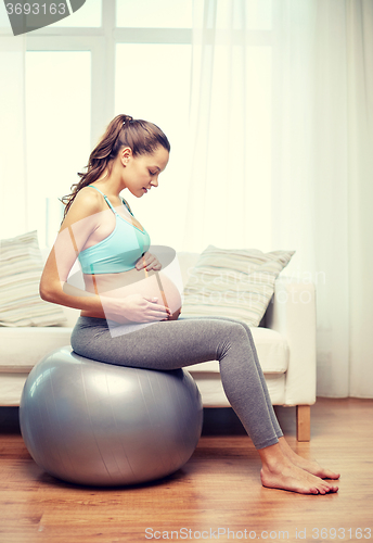 Image of happy pregnant woman exercising on fitball at home