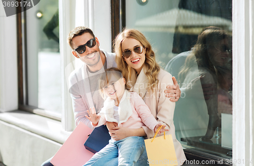 Image of happy family with child and shopping bags in city