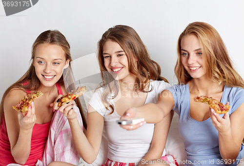 Image of happy friends eating pizza and watching tv at home