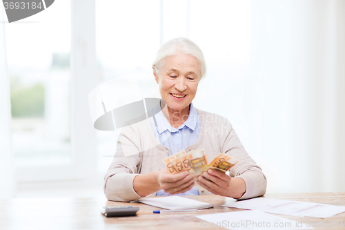 Image of senior woman with money and papers at home