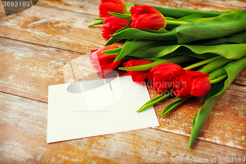 Image of close up of red tulips and blank paper or letter