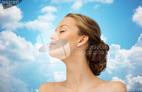 Image of young woman face and shoulders over blue sky