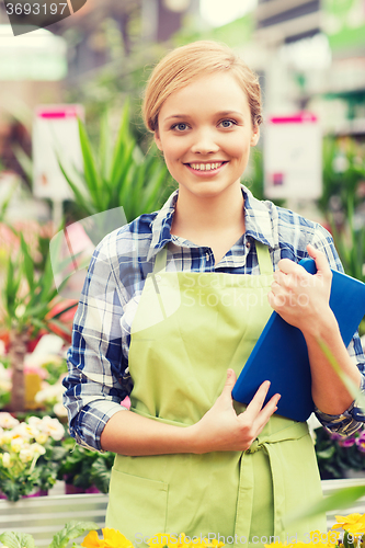 Image of happy woman with tablet pc in greenhouse