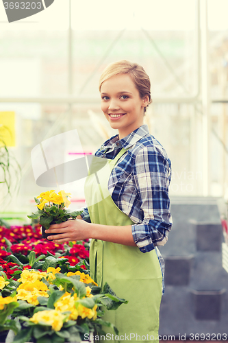 Image of happy woman holding flowers in greenhouse