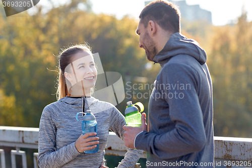 Image of smiling couple with bottles of water outdoors