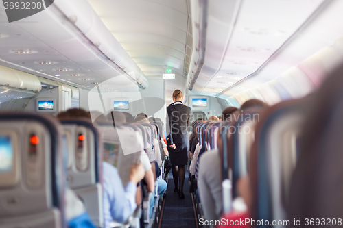 Image of Stewardess and passengers on commercial airplane.