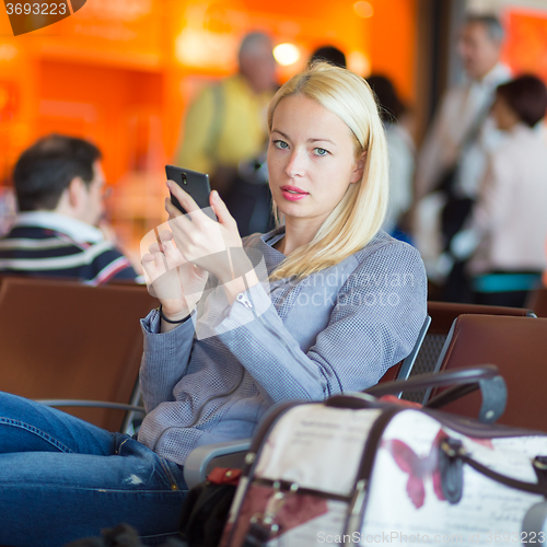 Image of Female traveler using cell phone while waiting.