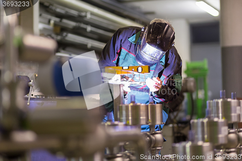 Image of Industrial worker welding in metal factory.