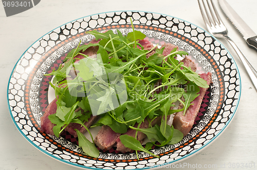 Image of Sliced beef cooked in the oven with salt, pepper and rocket