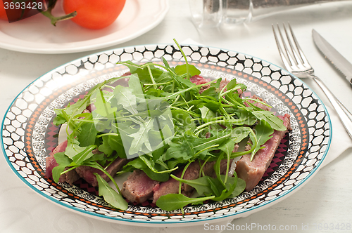 Image of Sliced beef cooked in the oven with salt, pepper and rocket