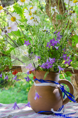 Image of Jug with a bouquet of summer flowers on a table in the garden