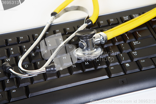 Image of Yellow phonendoscope and black keyboard
