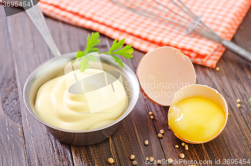 Image of mayonnaise in metal spoon on wooden board