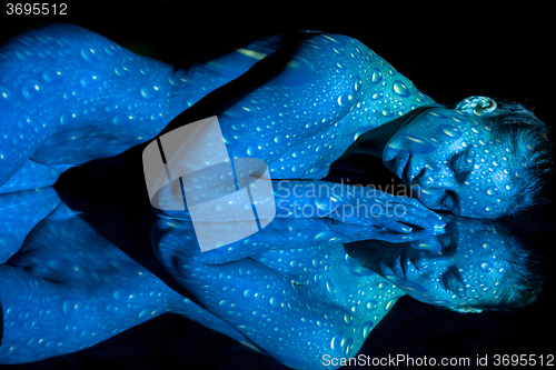 Image of The  body of woman with blue pattern and its reflection