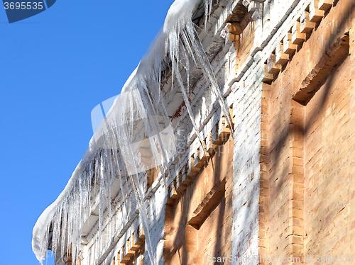Image of Snow-covered roof of old house with icicles