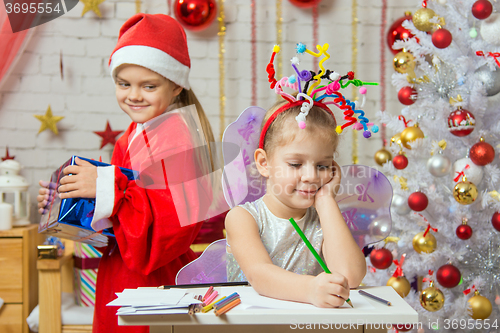 Image of Girl sits at a table with fireworks on the head, Santa Claus brings her Christmas gift