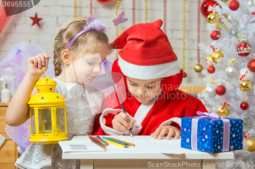 Image of Father Frost wrote a congratulatory letter to the assistant fairy standing next to the lifting arm candleholder