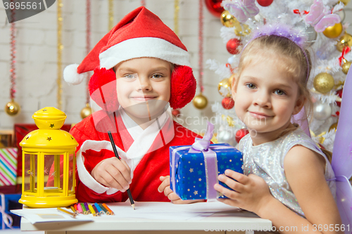 Image of Santa Claus and fairy helper prepared greeting cards and presents