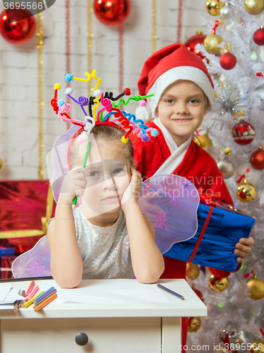 Image of Girl sits at a table with fireworks on the head, santa claus her ready to give her a gift