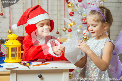 Image of Girl dressed as Santa Claus puts a congratulatory letter in the envelope that holds the girl fairy