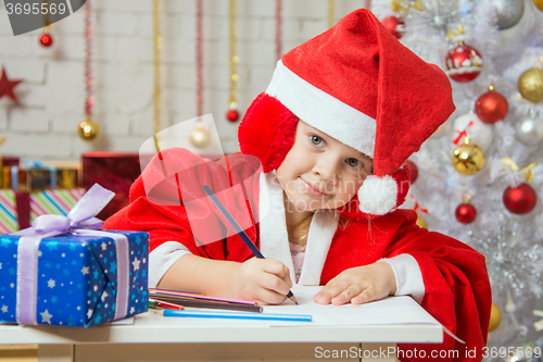 Image of The girl with enthusiasm draws a Christmas card