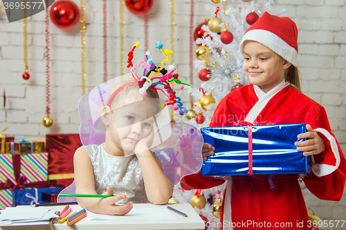 Image of Girl sits at a table with fireworks on the head, Santa Claus brings her a gift