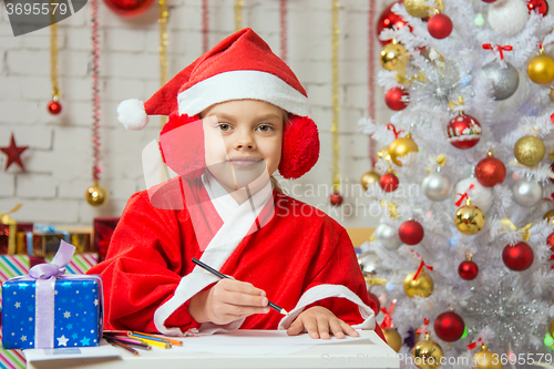 Image of Girl dressed as Santa Claus prepares New Years greetings