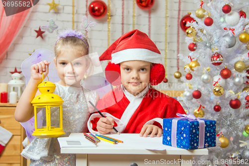 Image of  Father Frost wrote a congratulatory letter to the assistant fairy standing next to a candlestick in his hand