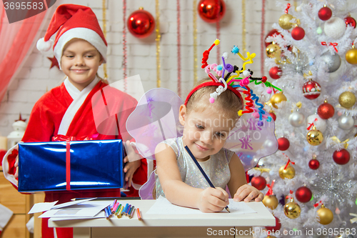Image of Girl sits at a table with fireworks on the head, Santa Claus is preparing to surprise her